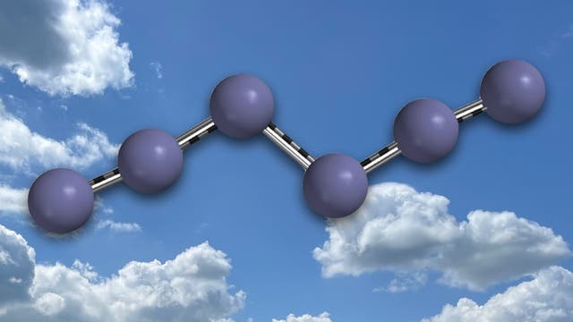 Eine chemische Molekülstruktur mit sechs violetten Kugeln, die durch graue Stäbe verbunden sind, schwebt vor einem Hintergrund aus blauem Himmel und weißen, flauschigen Wolken. Je drei Kugeln sind in einer Linie angeordnet, beide Dreiergruppen sind durch eine gewinkelte Bindung gegeneinander versetzt.
